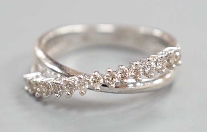 A modern 18ct white gold and diamond chip set half hoop crossover ring, size O, gross weight 3.9 grams.